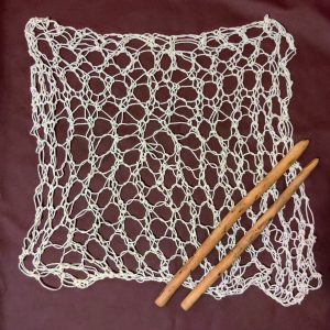 A knit mesh panel with large wooden knitting needles